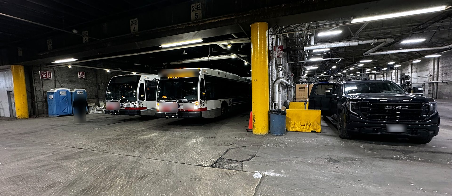 WTM pickup parked beside transit buses inside a bus garage