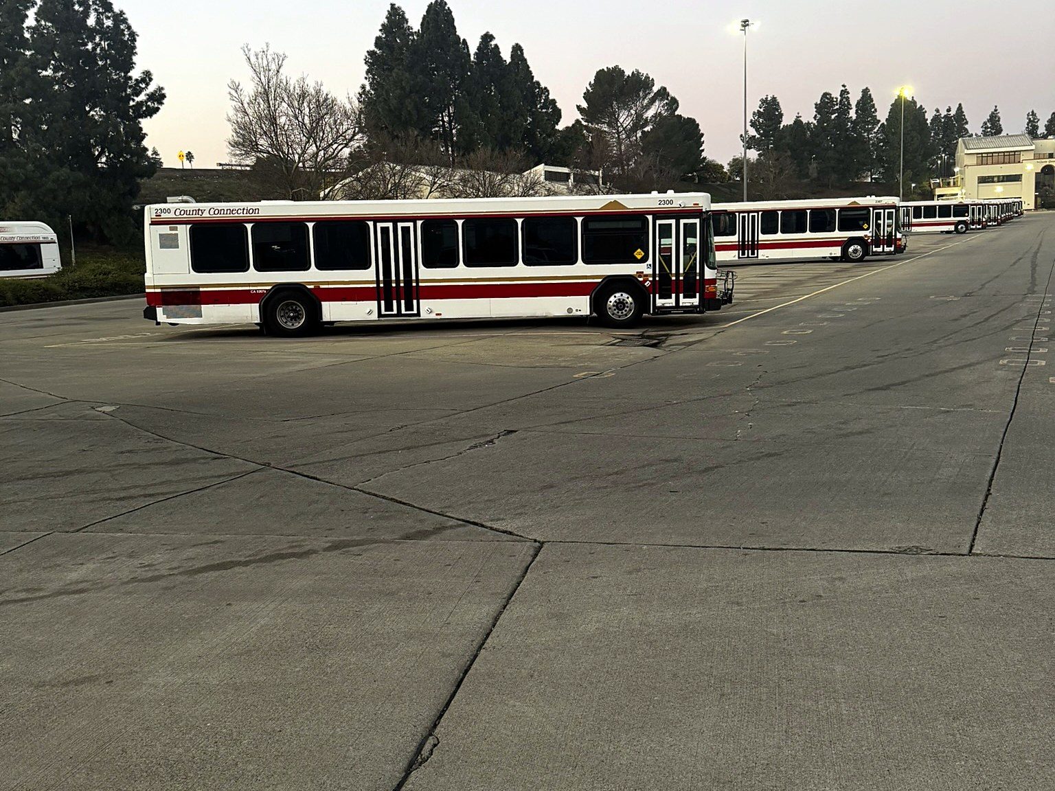Transit buses parked in a yard at dusk